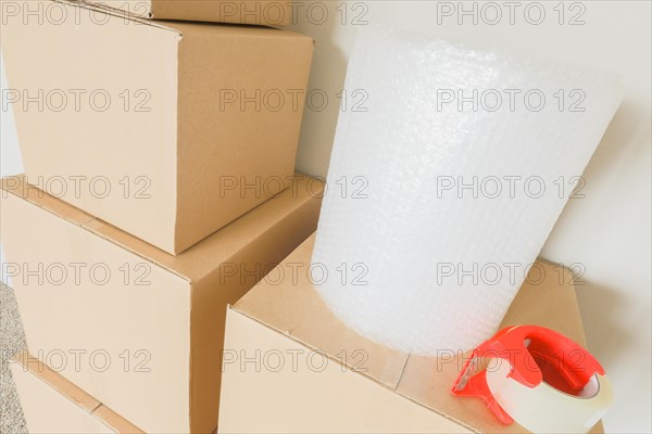 Variety of packed moving boxes with materials in empty room against wall