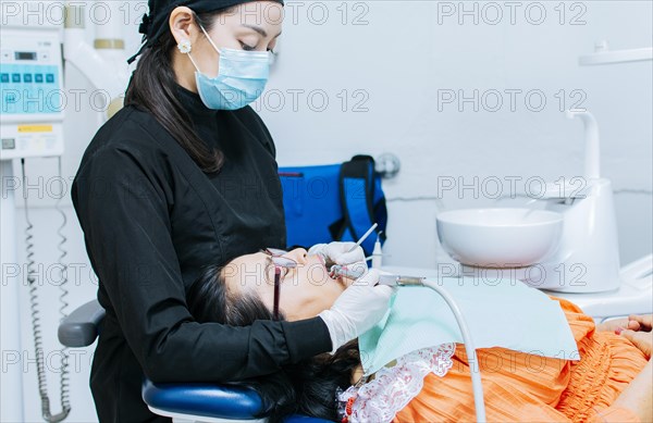 The stomatologist cleaning a patient's teeth