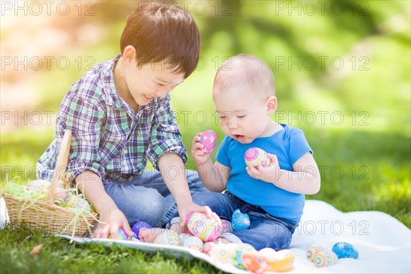 mixed-race chinese and caucasian boys outside in park playing with easter eggs