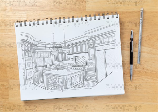 Sketch pad on desk top with drawing of custom kitchen interior next to engineering pencil and ruler scale