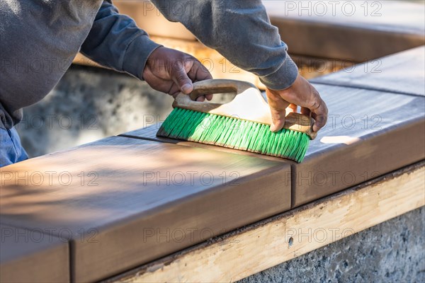 Construction worker using brush on wet cement forming coping around new pool