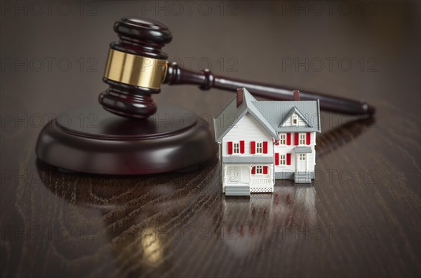 Gavel and small model house on wooden table