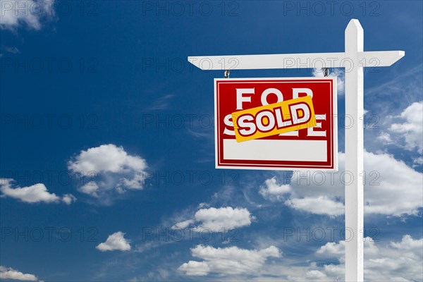 Left facing sold for sale real estate sign over blue sky and clouds with room for your text