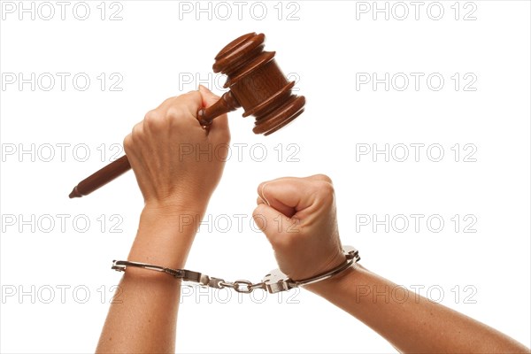 Handcuffed woman holding wooden gavel in her fist isolated on a white background