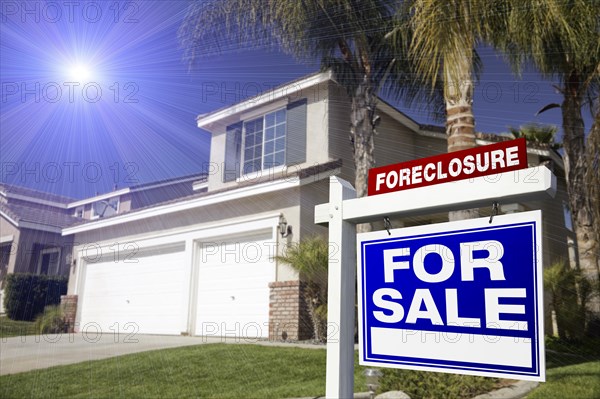 Blue foreclosure for sale real estate sign in front of house with blue star-burst in sky