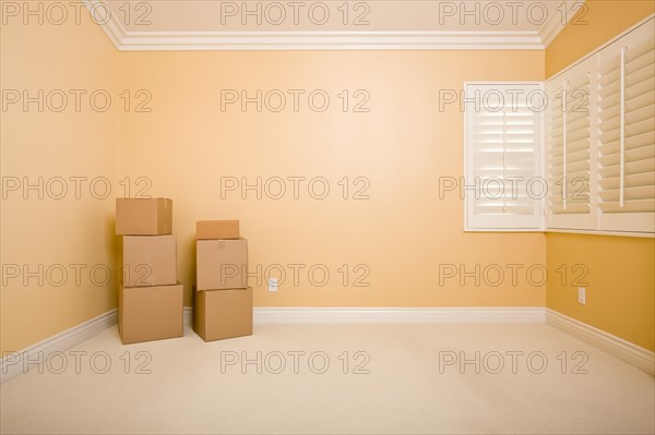 Moving boxes in empty room with copy space on blank wall