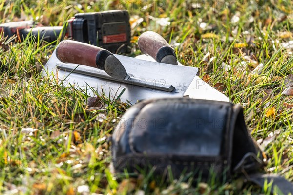 Cement trowels and tools on grass at construction site