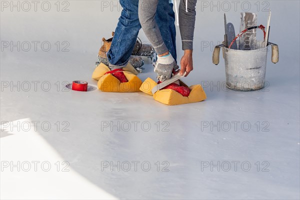 Worker taping sponges on shoes to smooth wet pool plaster