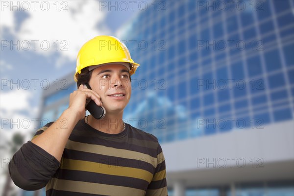 Handsome hispanic male contractor on cell phone in front of corporate building