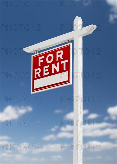 Left facing for rent real estate sign on a blue sky with clouds