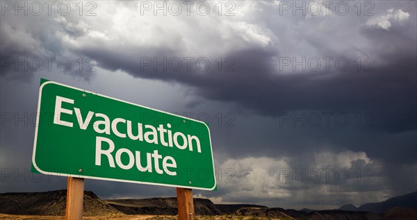 Evacuation route green road sign with dramatic clouds and rain