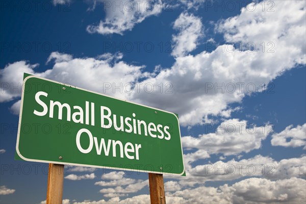 Small business owner green road sign with dramatic clouds and sky