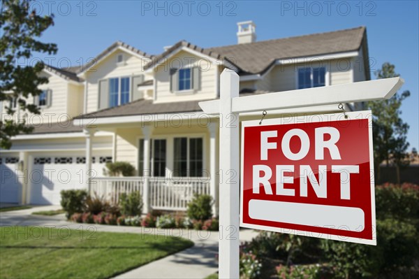 Left facing red for rent real estate sign in front of beautiful house