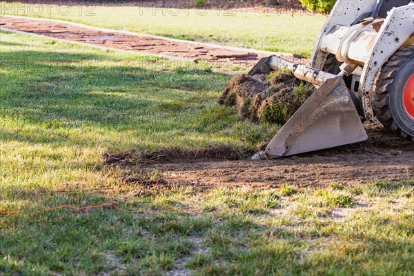 Small bulldozer removing grass from yard preparing for pool installation