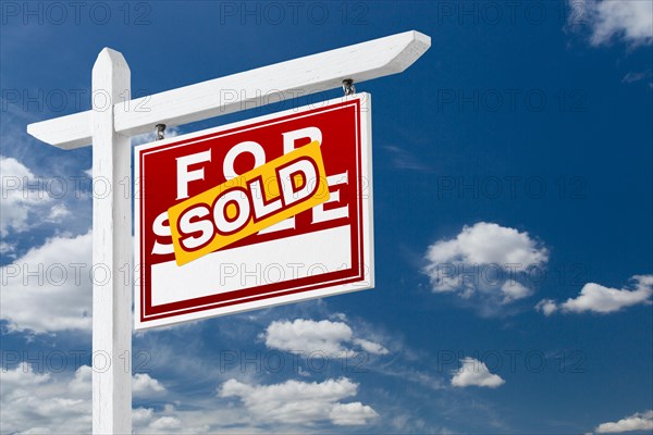 Right facing sold for sale real estate sign over blue sky and clouds with room for your text