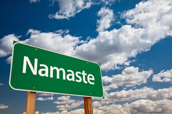 Namaste green road sign with copy room over the dramatic clouds and sky