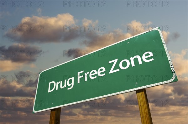 Drug free zone green road sign over dramatic clouds and sky
