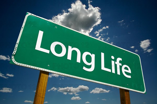 Long life green road sign with dramatic clouds and sky