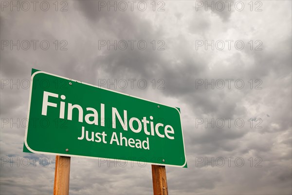 Final notice just ahead green road sign with dramatic storm clouds and sky