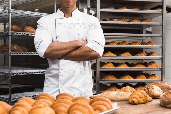 midsection male baker with his arms crossed standing bakery