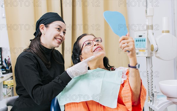 Satisfied female client in dental clinic looking at mirror