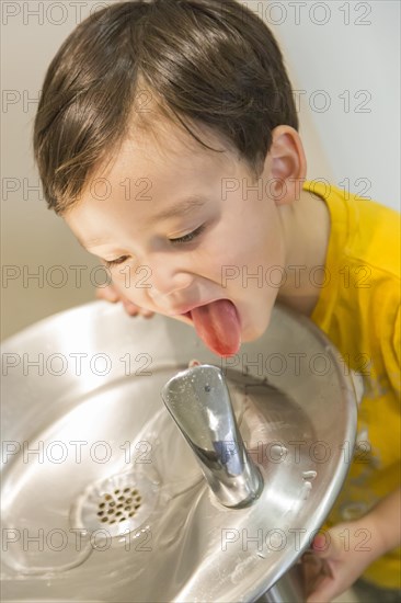 mixed-race boy drinking from the fresh water fountain