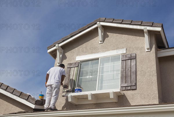 Busy house painter painting the trim and shutters of A home
