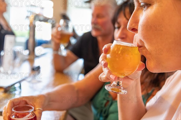 Female sipping glass of micro brew beer at bar with friends