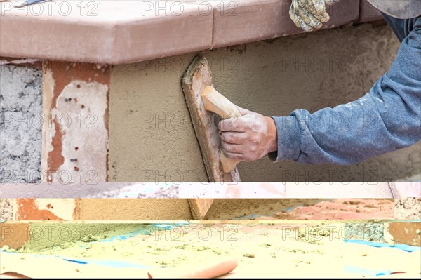 Worker smoothing cement with wooden float at construction site