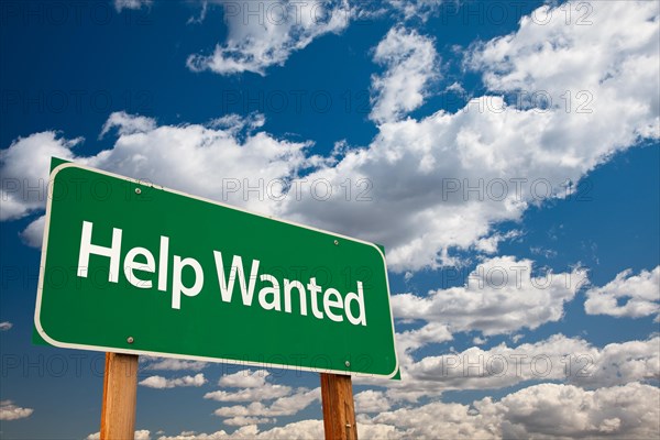 Help wanted green road sign with copy room over the dramatic clouds and sky