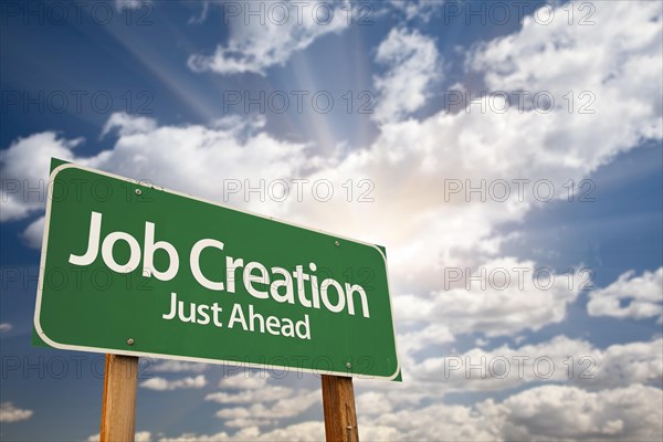 Job creation green road sign against dramatic sky