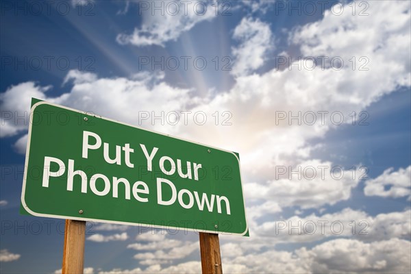 Put your phone down green road sign with dramatic sky