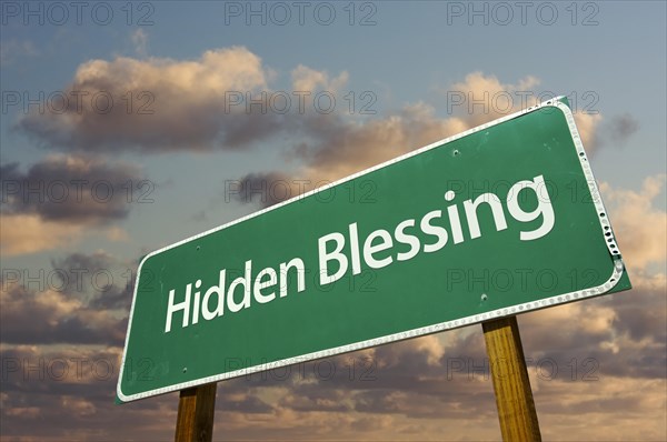 Hidden blessing green road sign with dramatic clouds and sky