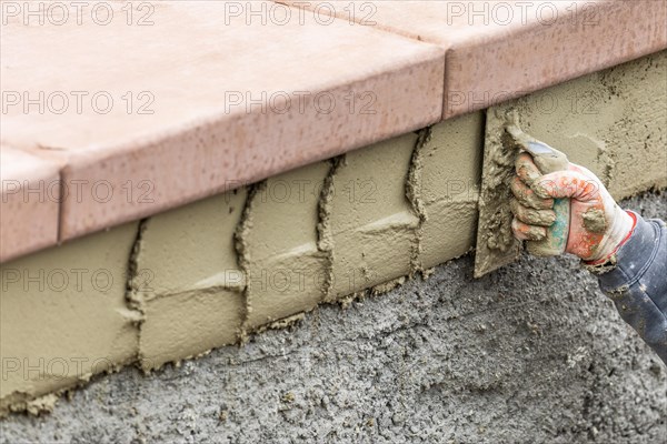 Tile worker applying cement with trowel at pool construction site