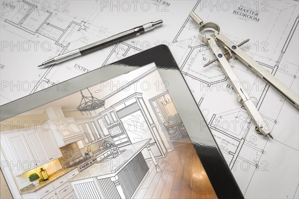Computer tablet showing kitchen illustration sitting on house plans with pencil and compass