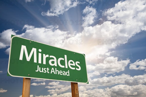 Miracles green road sign against clouds and sunburst