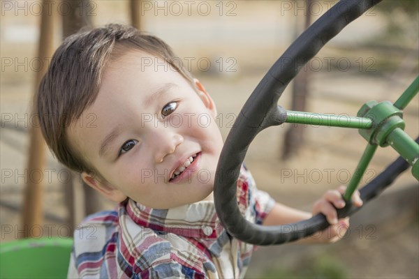 Adorable mixed-race young boy playing on the tractor at the pumpkin patch