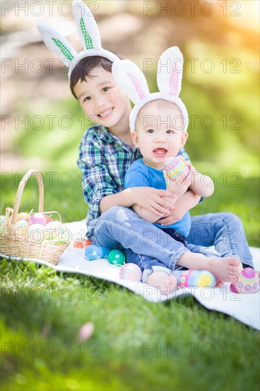 mixed-race chinese and caucasian boys outside in park playing with easter eggs
