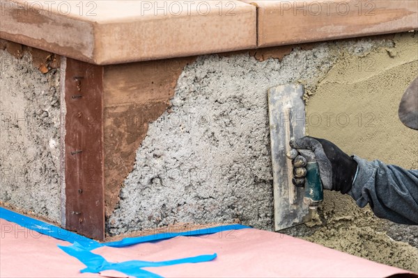 Tile worker applying cement with trowel at pool construction site