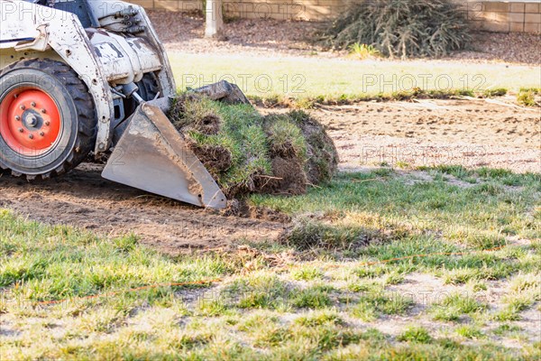 Small bulldozer removing grass from yard preparing for pool installation