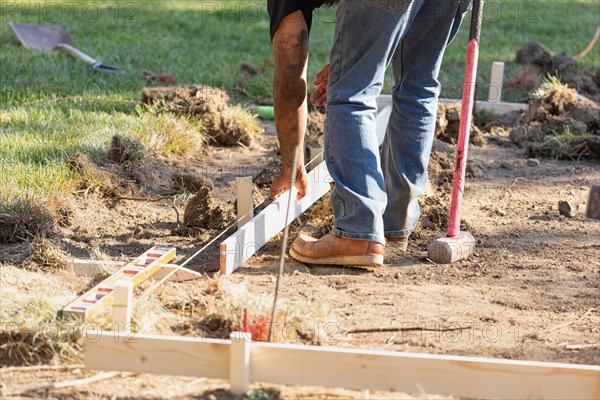 Worker installing stakes and lumber guides at construction site