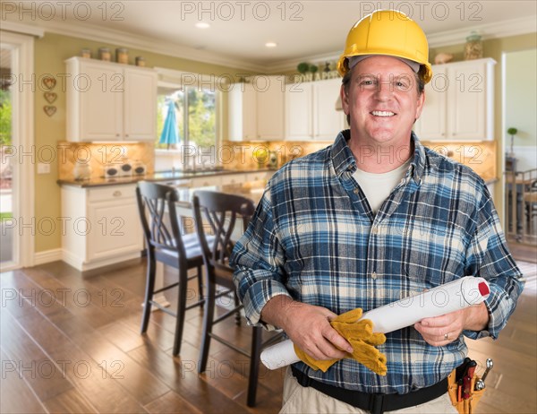 Contractor with plans and hard hat inside custom kitchen