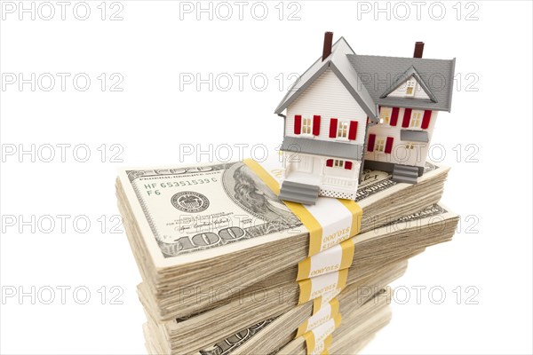 Small house on stacks of hundred dollar bills isolated on a white background