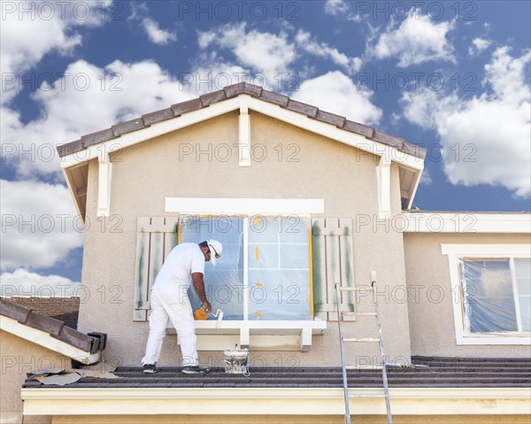 Busy house painter painting the trim and shutters of A home