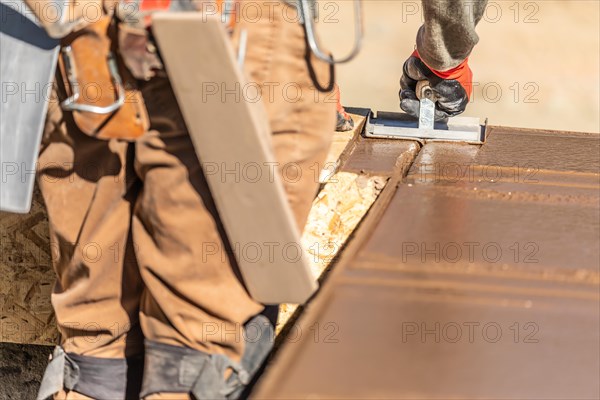 Construction worker using hand groover on wet cement forming coping around new pool