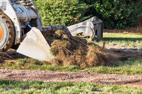 Small bulldozer removing grass from yard preparing for pool installation