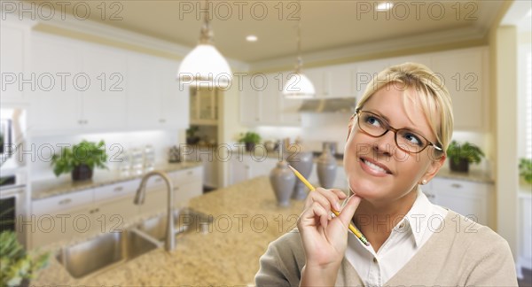 Attractive daydreaming woman with pencil inside beautiful custom kitchen