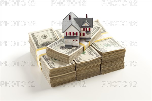 Small house on stacks of hundred dollar bills isolated on a white background