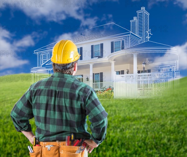 Contractor standing outdoors looking over grass site with ghosted house