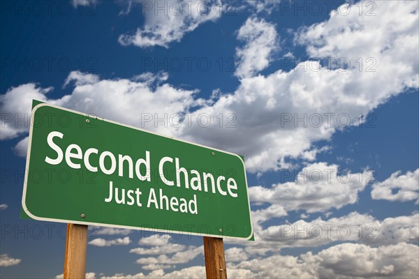 Second chance just ahead green road sign over dramatic clouds and sky